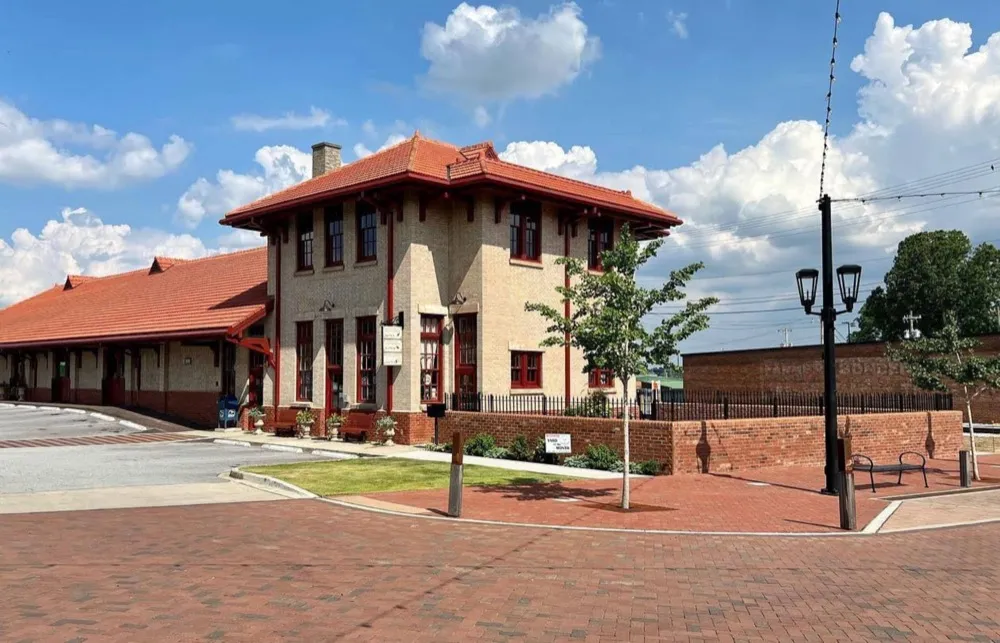 Historic Greer Depot, a two-story brick railroad depot with a red tile roof, now anchoring downtown Greer Station